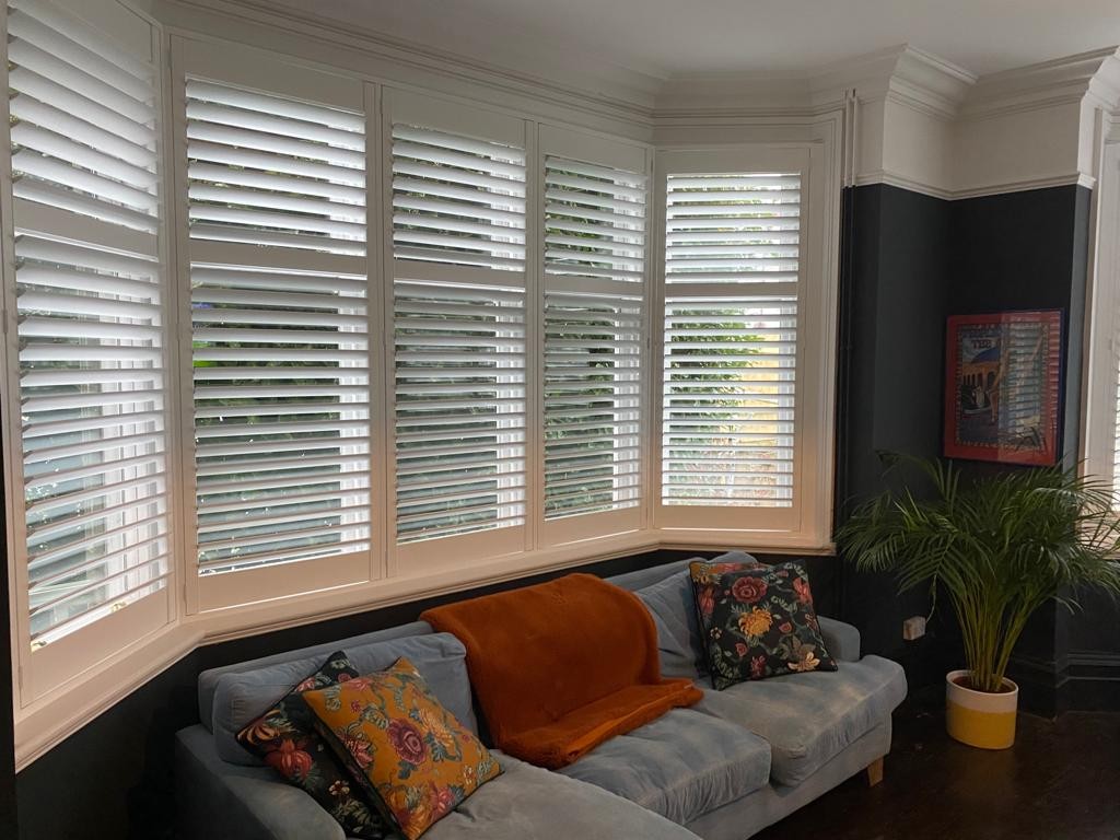 Finished shutters fitted in a bay window above a sofa